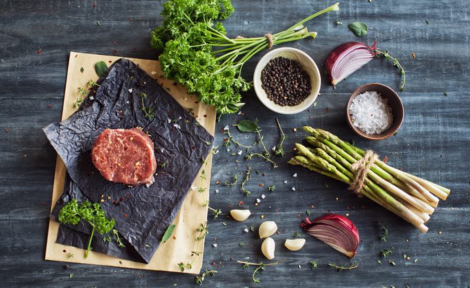 Raw tenderloin steak with seasoning, garlic, and asparagus